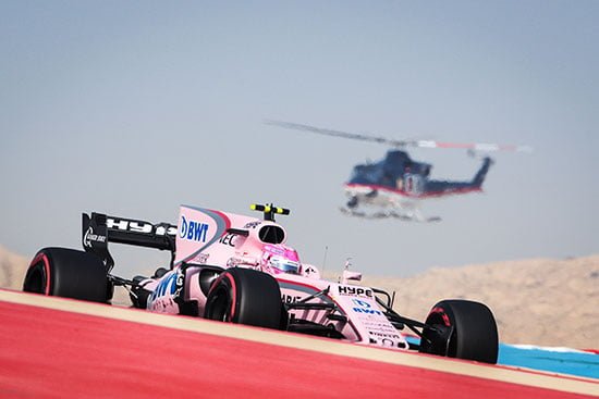 F1 car races in pink at the Bahrain Circuit.