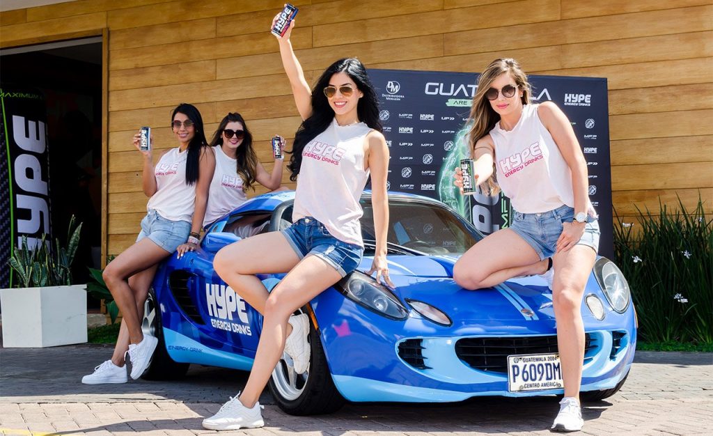 Four girls pose around a blue sports car.