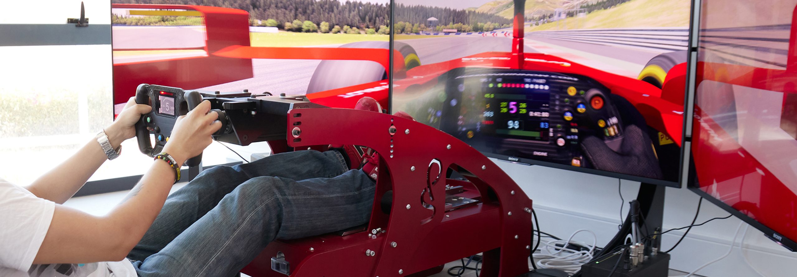 F1 simulator in red with three wide screen monitor.
